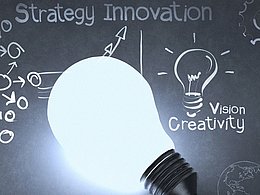 Glühbirne vor einer beschriebenen Tafel zum Thema Innovationsstrategie