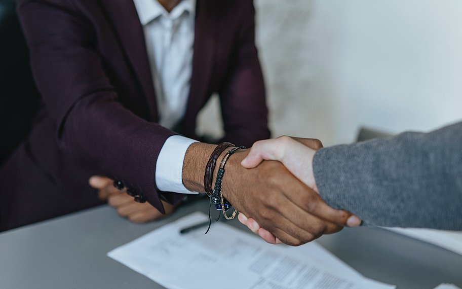 Foto: Mann in dunkler Anzugjacke hält die Hand einer anderen Person. © Olia Danilevich | pexels.com